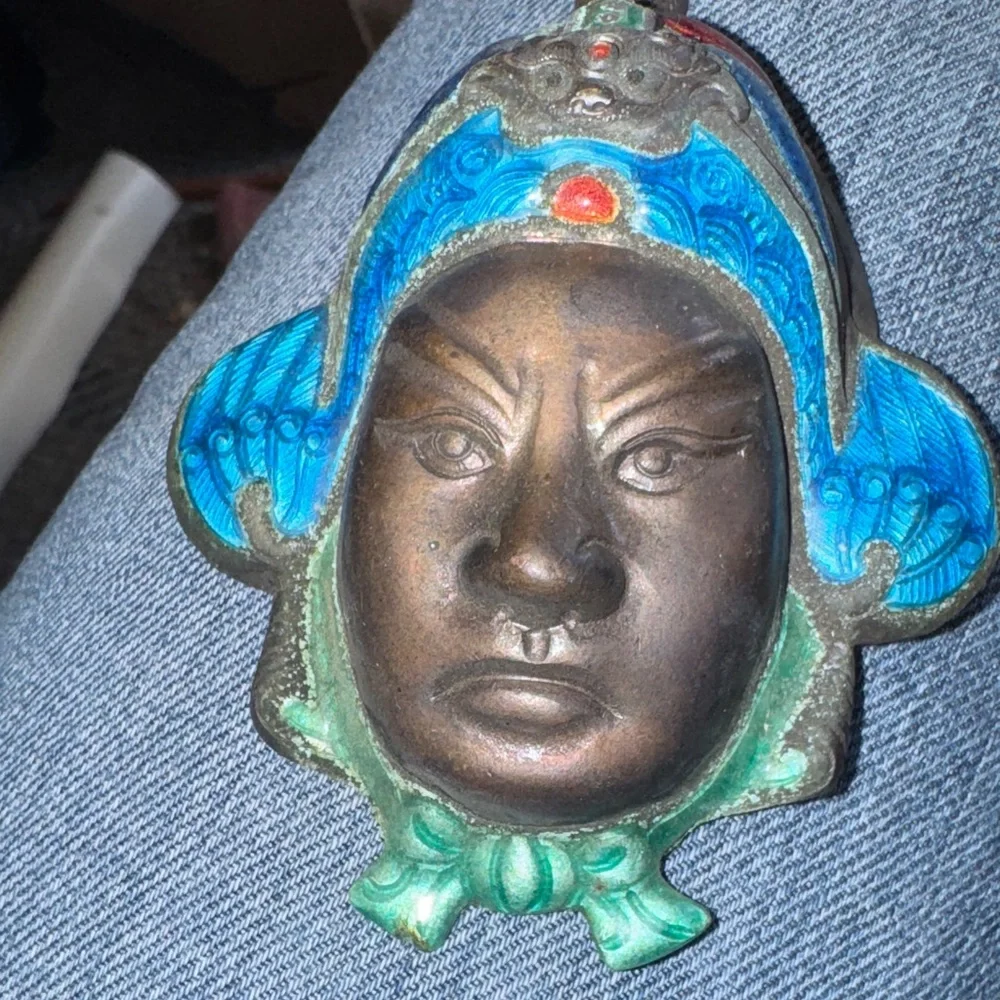Vintage enameled metal decorative mask of an Asian man's face.